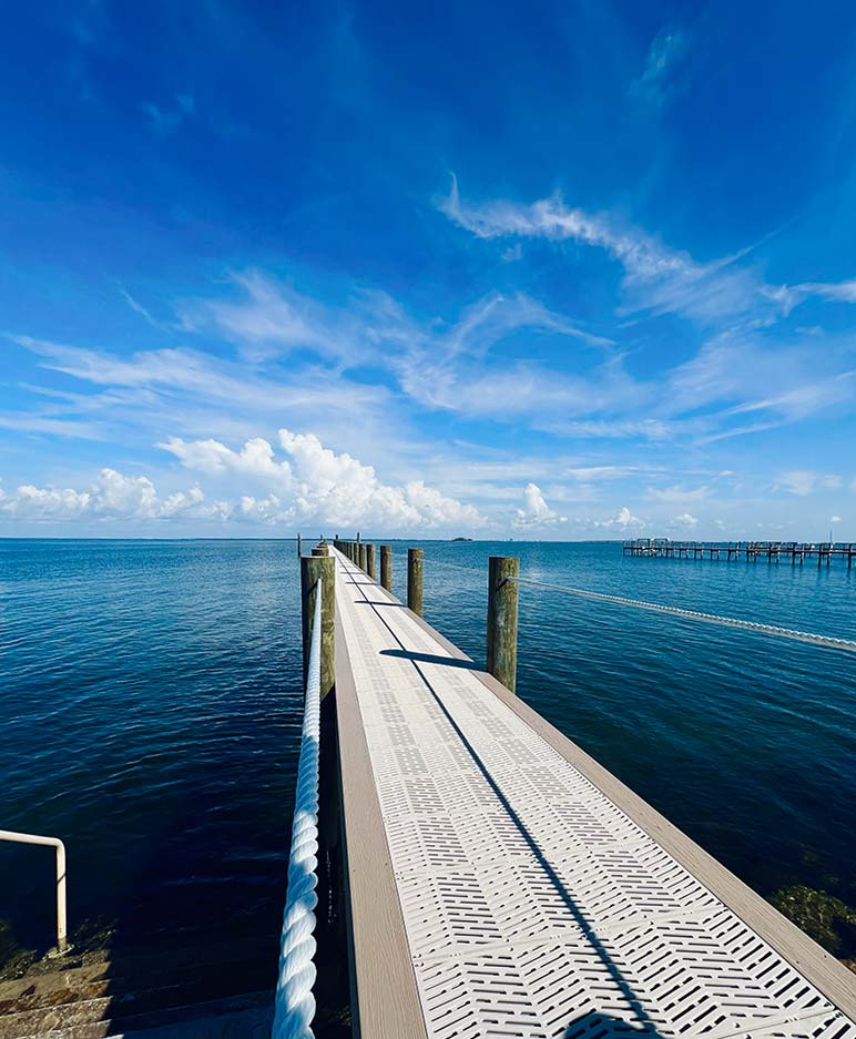 Blue sky day showing a custom built dock stretching out into a bay