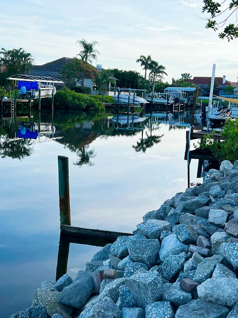 sunset image showing a seawall and docks along a coastal canal